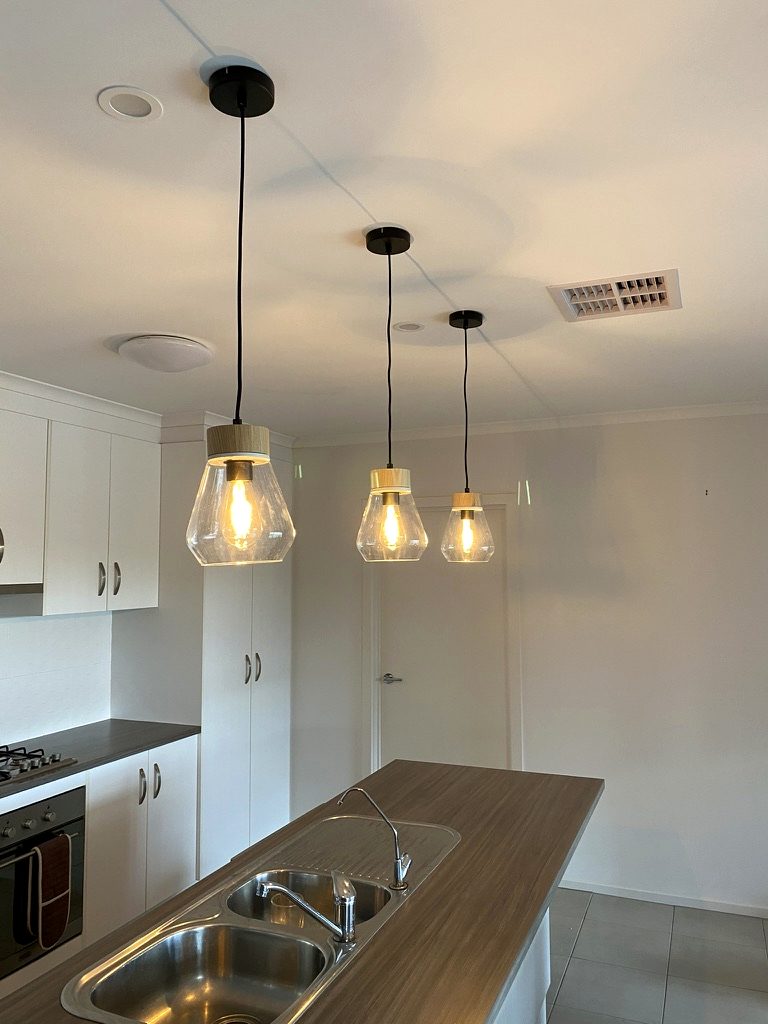 Three pendant lights installed over a kitchen island